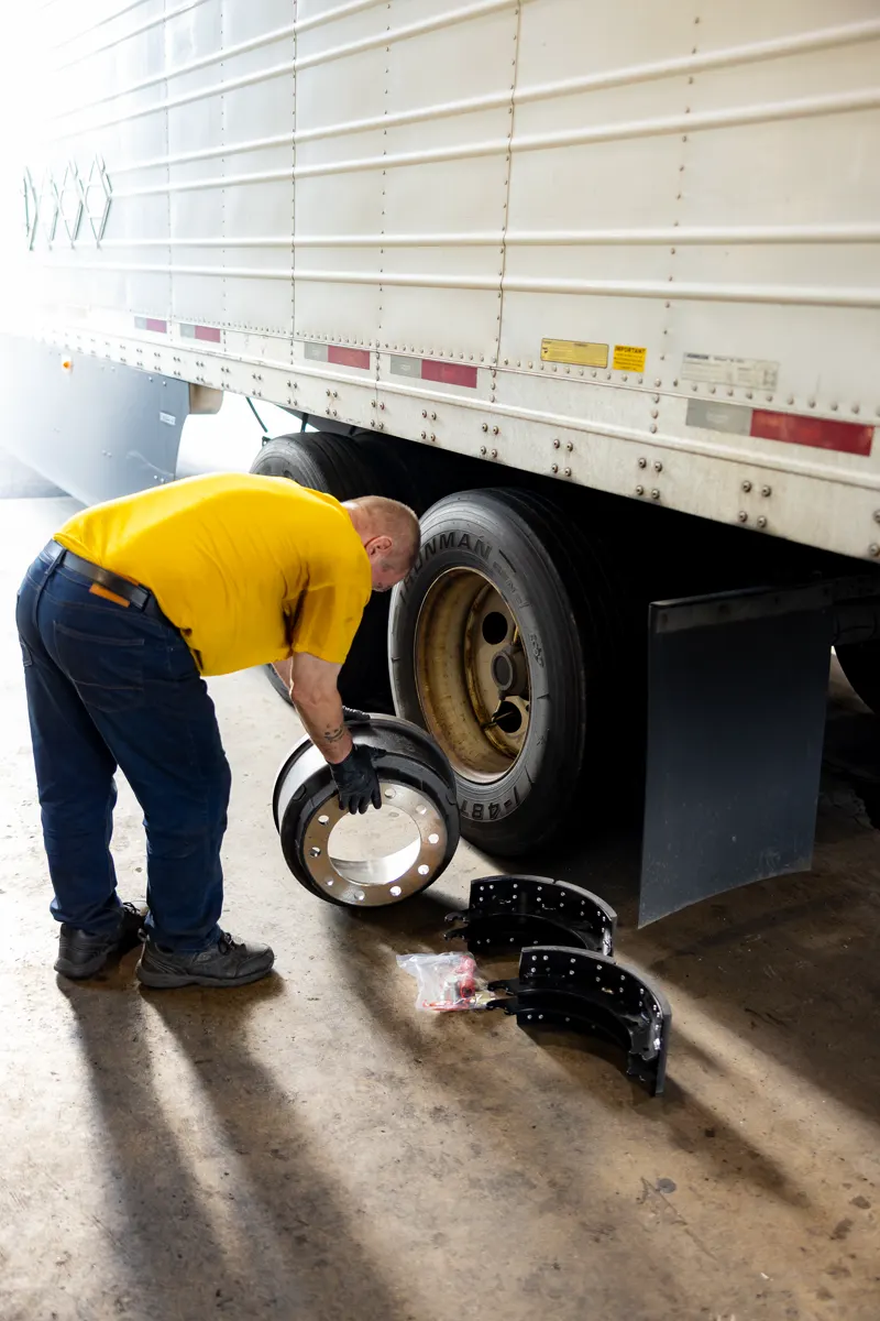 Technician replacing brake shoes on a trailer axle